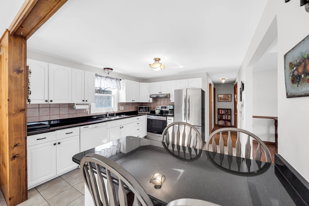 21 Martin Farms Road Hampden, MA 01036 - Photo 7 of 42 a kitchen with stainless steel appliances granite countertop a sink dishwasher a stove a refrigerator with a dining table and chairs