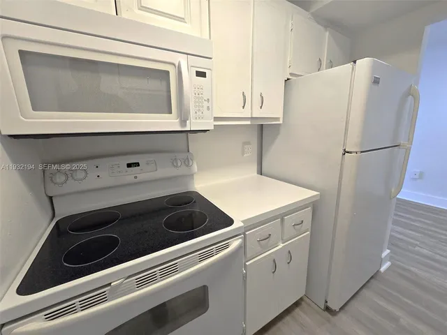 a kitchen with white cabinets and white appliances