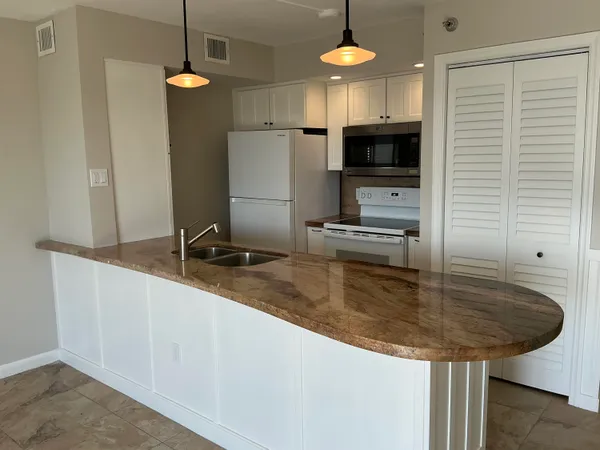 a kitchen with stainless steel appliances granite countertop a sink a microwave and a refrigerator