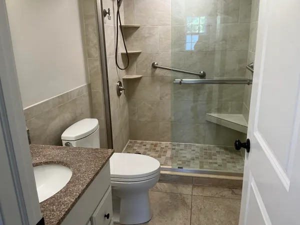 a bathroom with a granite countertop toilet a sink and a shower