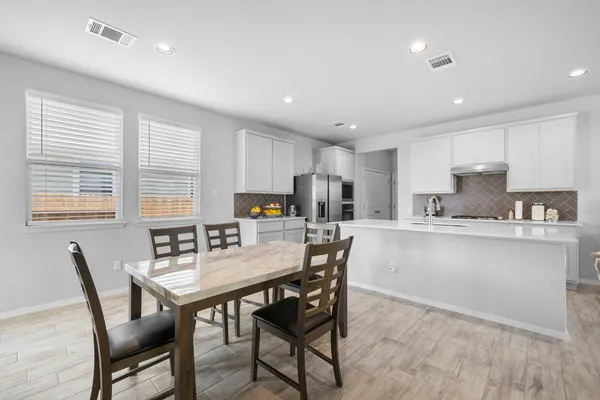 a kitchen with a dining table chairs and refrigerator
