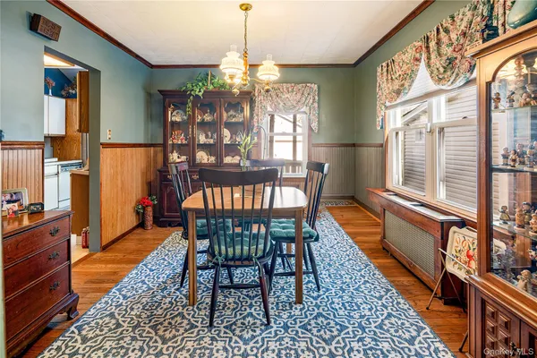 a dining room with wooden floor a chandelier a wooden table and chairs