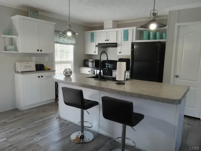 a kitchen with granite countertop a refrigerator a stove a sink and a dining table with wooden floor