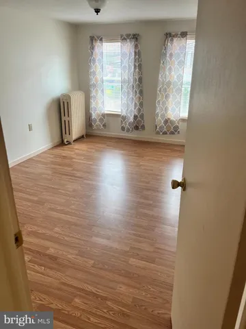 a view of empty room with window and wooden floor