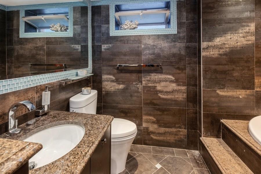 211 81st Street Brooklyn, NY 11209 - Photo 29 of 35 a bathroom with a granite countertop sink a toilet a mirror and shower