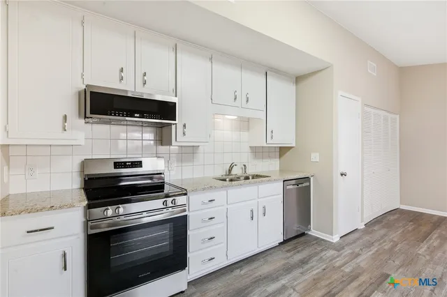 a kitchen with stainless steel appliances white cabinets and a stove top oven