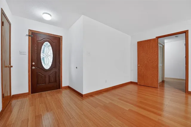 a view of an empty room with wooden floor fireplace and a window