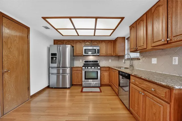 an empty room with wooden floor chandelier fan and windows