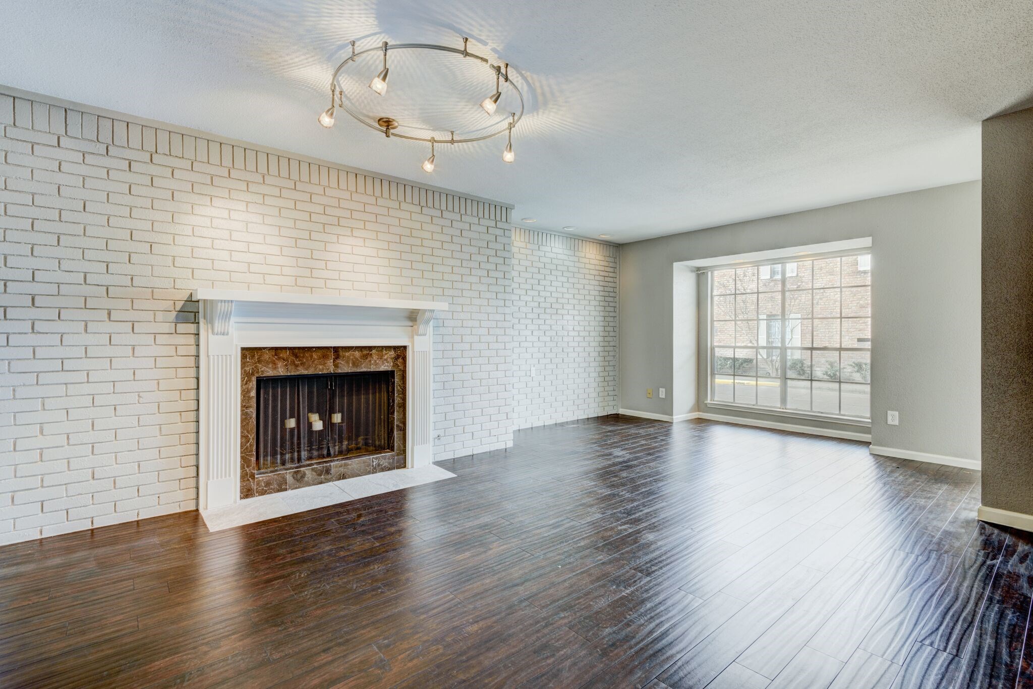 6444 Burgoyne Road, Unit 104 Houston, TX 77057 - Photo 2 of 17 Hardwood floors, brick accent wall and fireplace