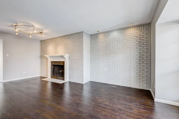 an empty room with wooden floor fireplace and windows