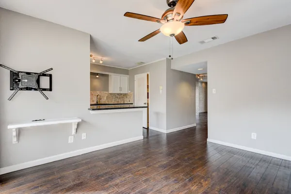 a view of empty room with wooden floor and fan