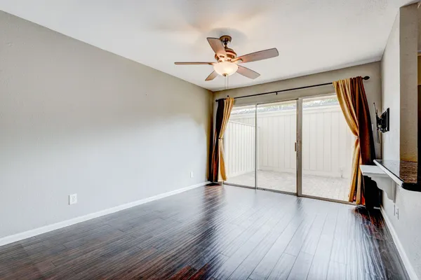 an empty room with wooden floor fan and windows