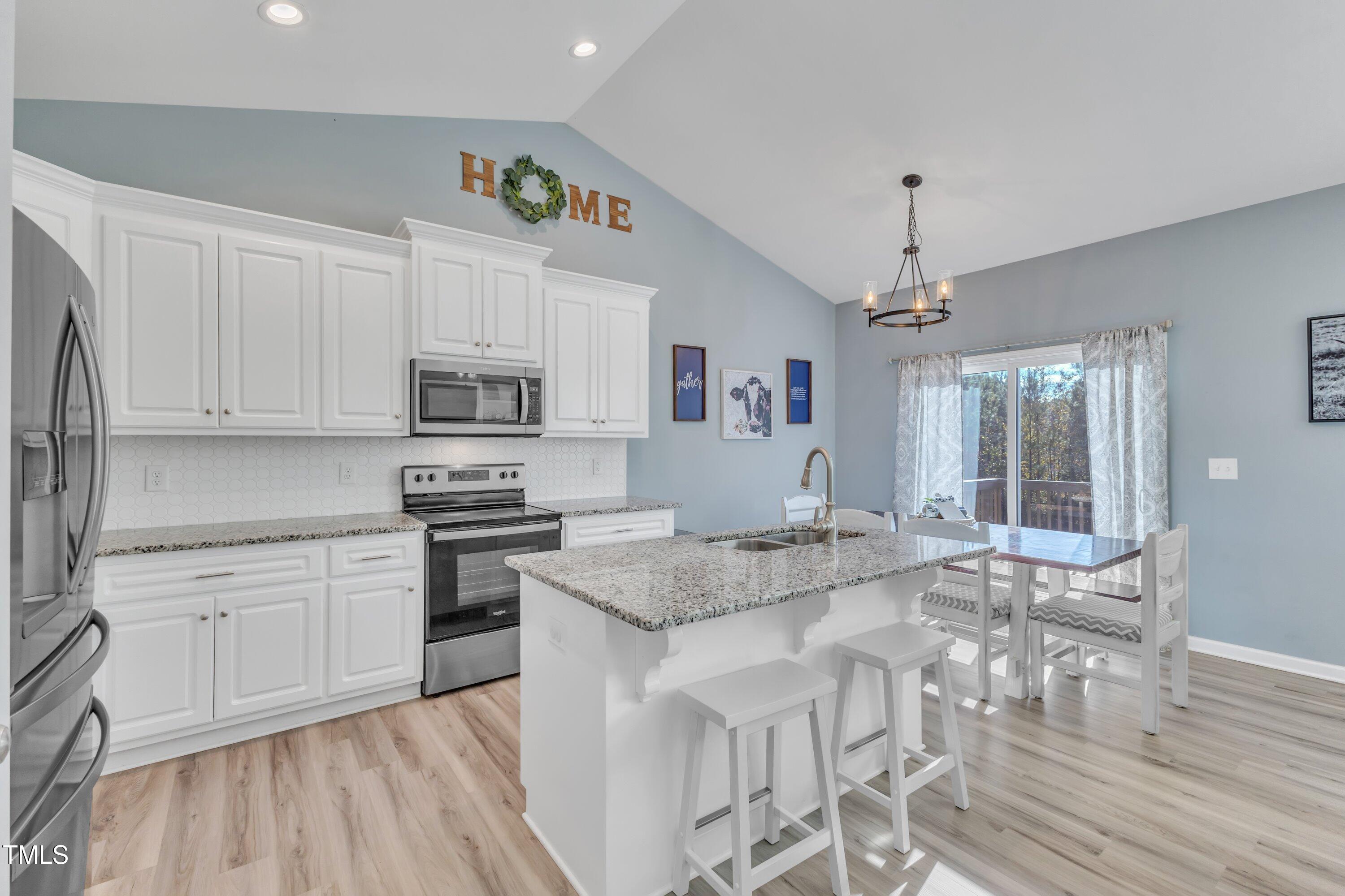 10387 Claude Lewis Road Middlesex, NC 27557 - Photo 10 of 37 a kitchen with stainless steel appliances granite countertop a stove top oven a sink dishwasher a dining table and chairs with wooden floor
