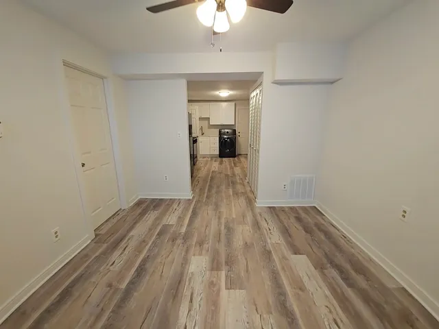a view of a room with wooden floor and a ceiling fan