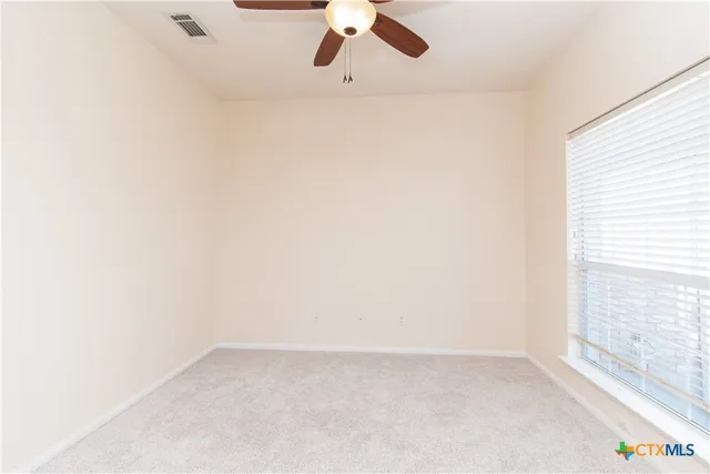 an empty room with a window and a ceiling fan