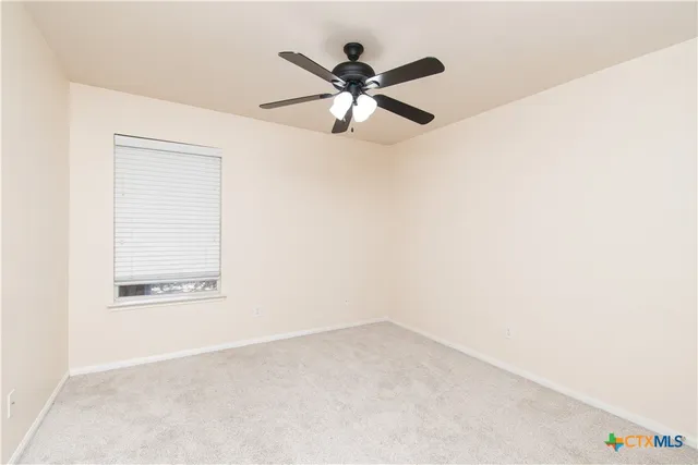 an empty room with a ceiling fan and a window