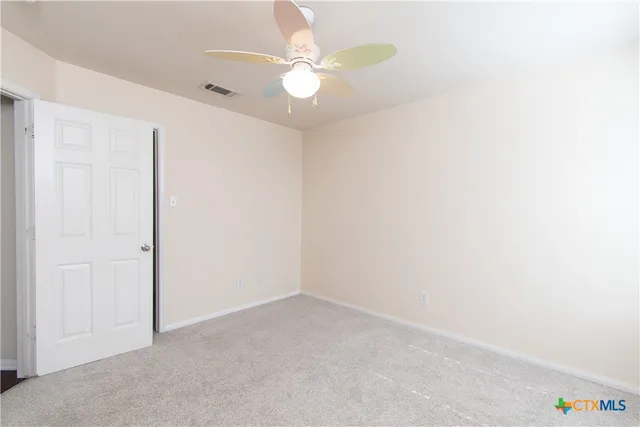 an empty room with a ceiling fan and a window