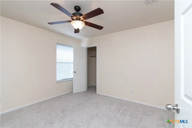 an empty room with a ceiling fan and a window