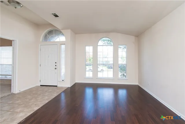 an empty room with wooden floor and windows