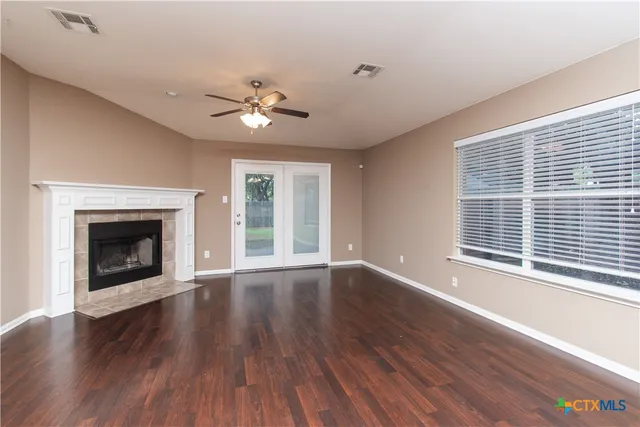a view of an empty room with wooden floor fireplace and a window