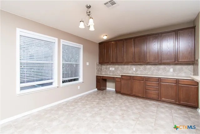a large kitchen with kitchen island granite countertop wooden cabinets a sink a window and stainless steel appliances