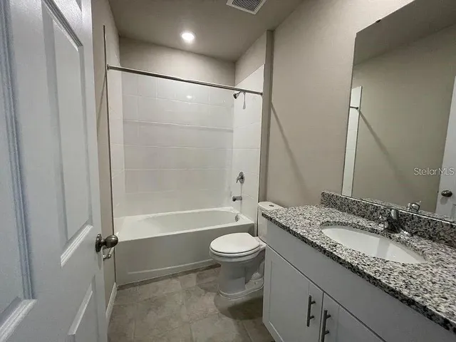 a bathroom with a granite countertop sink toilet mirror and shower