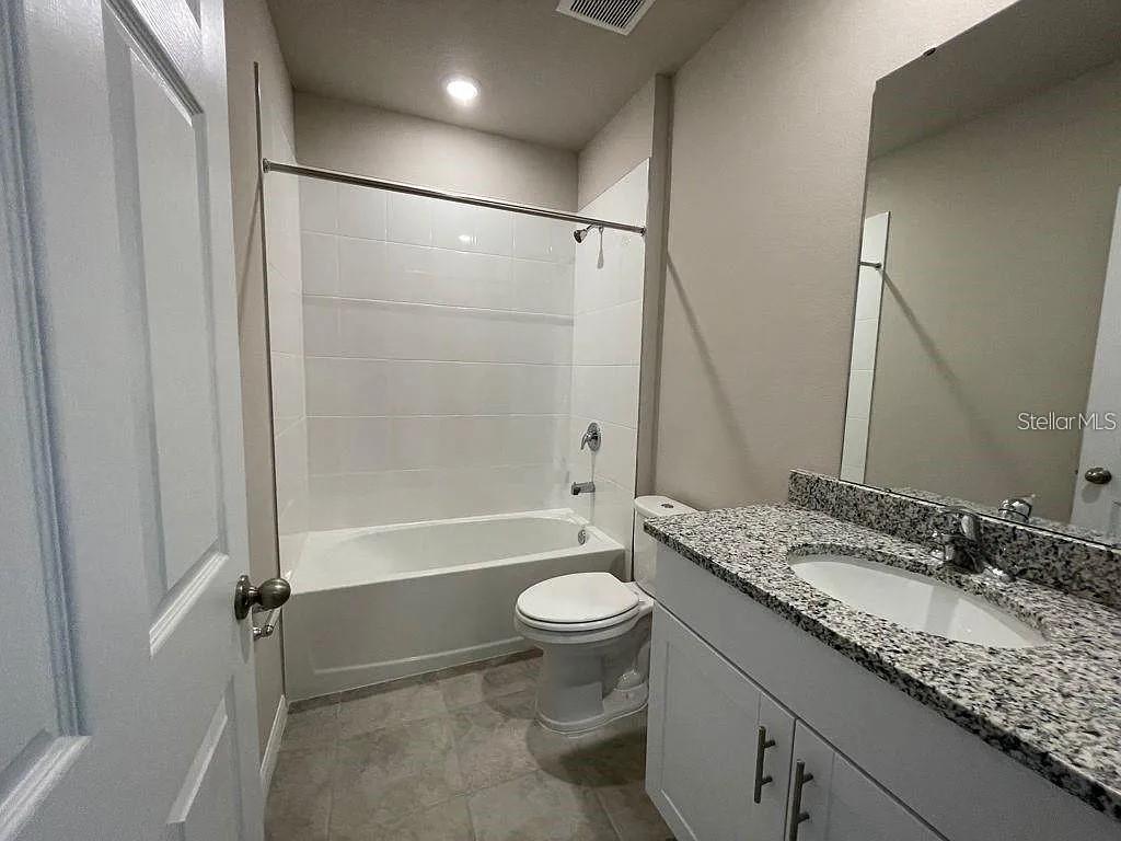 1274 Citrus Landings Boulevard Davenport, FL 33837 - Photo 16 of 20 a bathroom with a granite countertop sink toilet mirror and shower