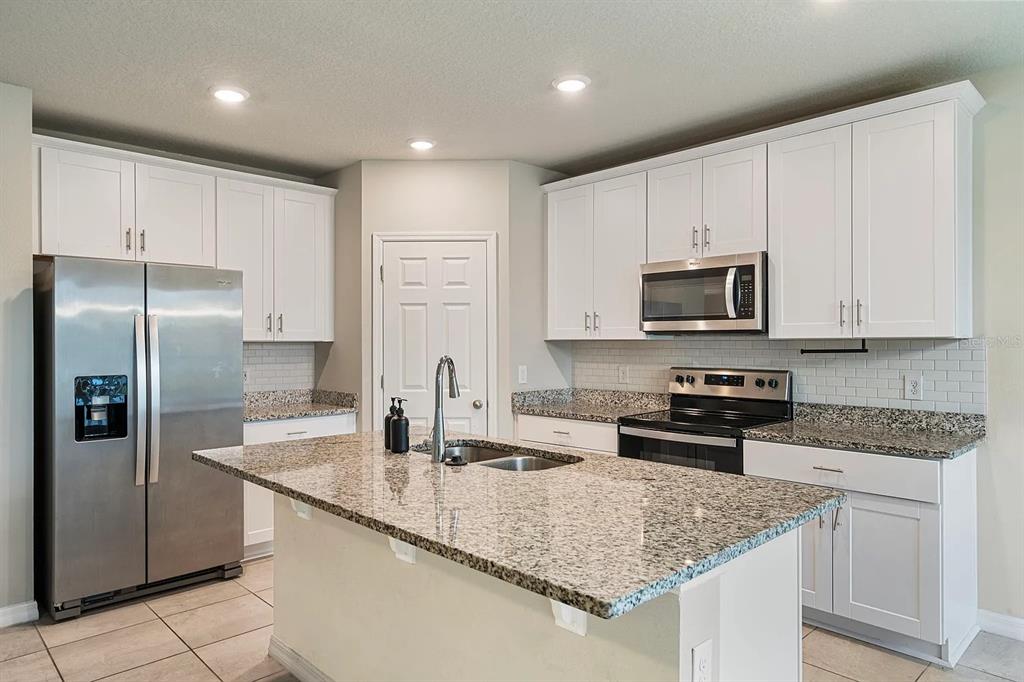 1274 Citrus Landings Boulevard Davenport, FL 33837 - Photo 3 of 20 a kitchen with kitchen island granite countertop a sink stove and refrigerator