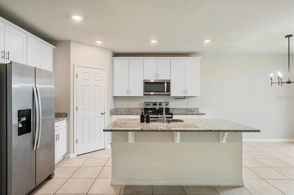 1274 Citrus Landings Boulevard Davenport, FL 33837 - Photo 4 of 20 a kitchen with kitchen island granite countertop a stove a refrigerator and a sink