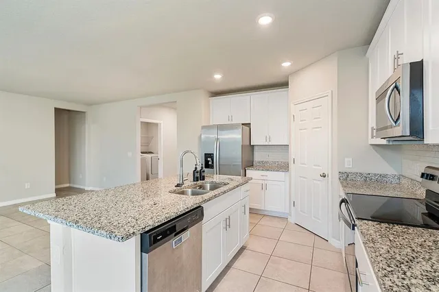 a kitchen with stainless steel appliances granite countertop a sink refrigerator and cabinets