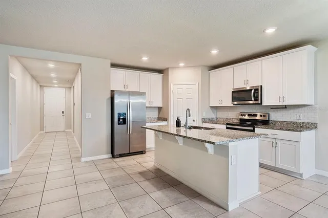 a kitchen with stainless steel appliances granite countertop a refrigerator and a stove top oven