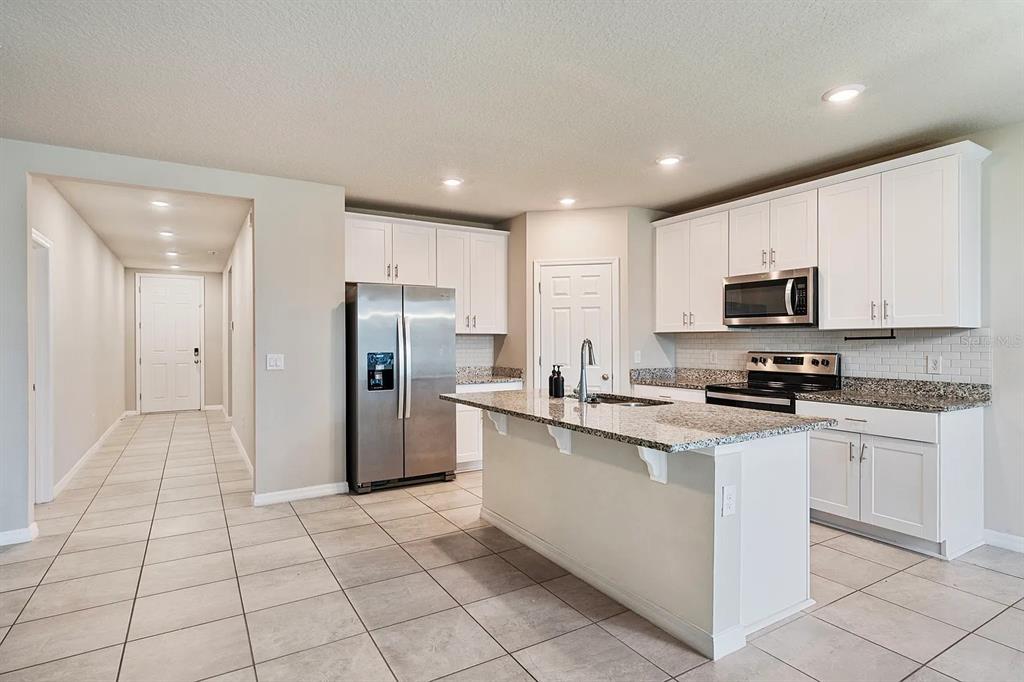 1274 Citrus Landings Boulevard Davenport, FL 33837 - Photo 6 of 20 a kitchen with stainless steel appliances granite countertop a refrigerator and a stove top oven