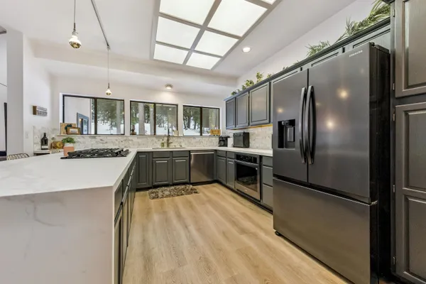 a large kitchen with kitchen island a large counter top stainless steel appliances and cabinets