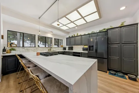 a kitchen with stainless steel appliances kitchen island granite countertop a table chairs and a refrigerator