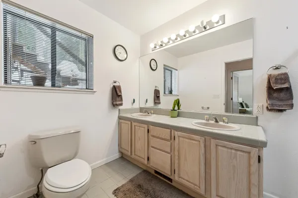 a bathroom with a toilet a sink a mirror and a window