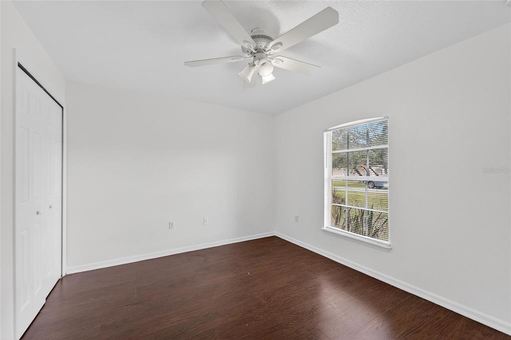 9010 Mc Cormick Street Spring Hill, FL 34608 - Photo 43 of 73 an empty room with wooden floor chandelier fan and windows