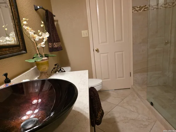 a spacious bedroom with a bed a dresser and a chandelier