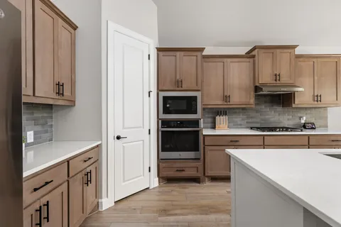 a kitchen with stainless steel appliances granite countertop a sink a stove a refrigerator cabinets and wooden floor