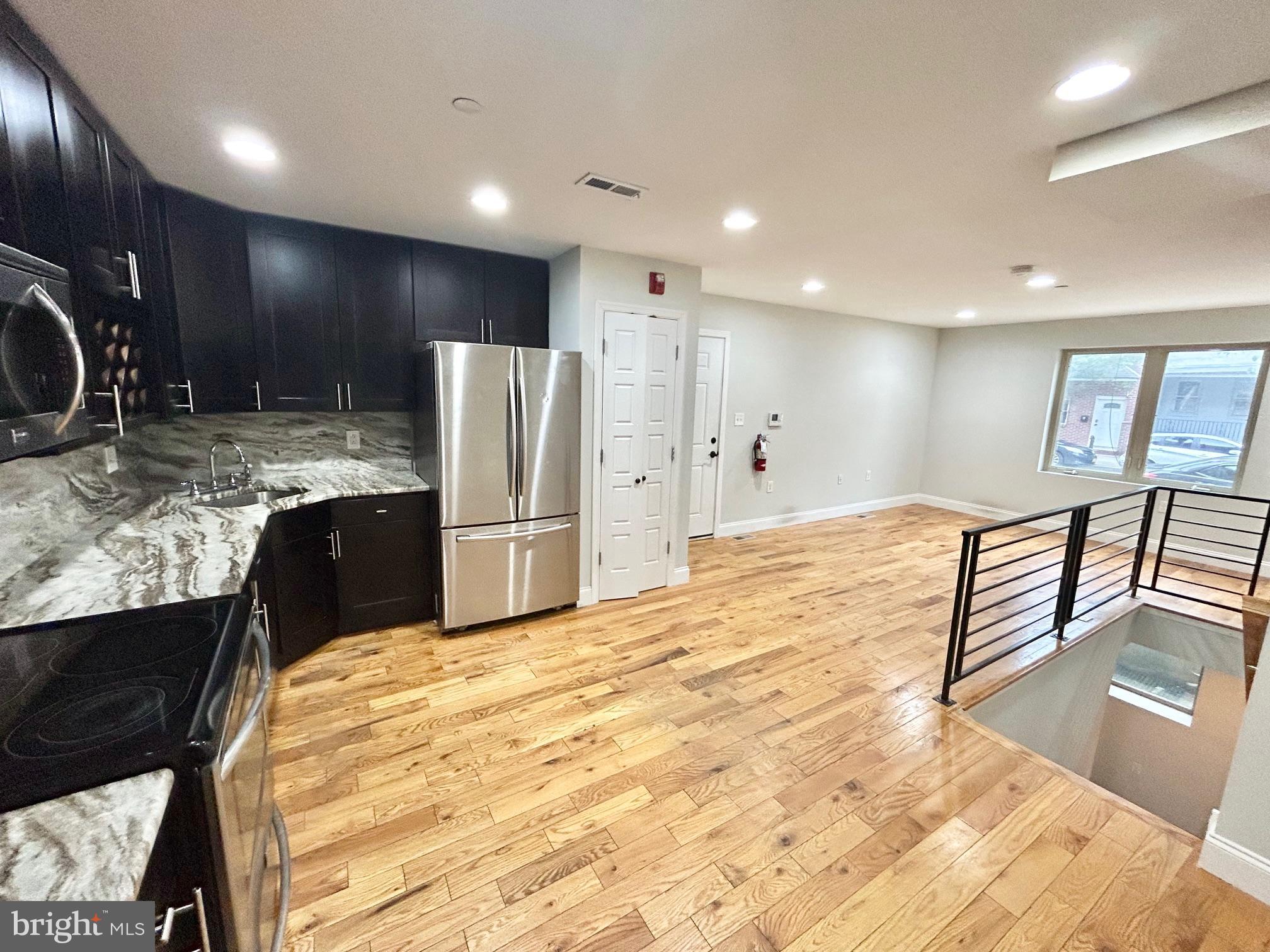 a large kitchen with stainless steel appliances kitchen island granite countertop a refrigerator and a sink
