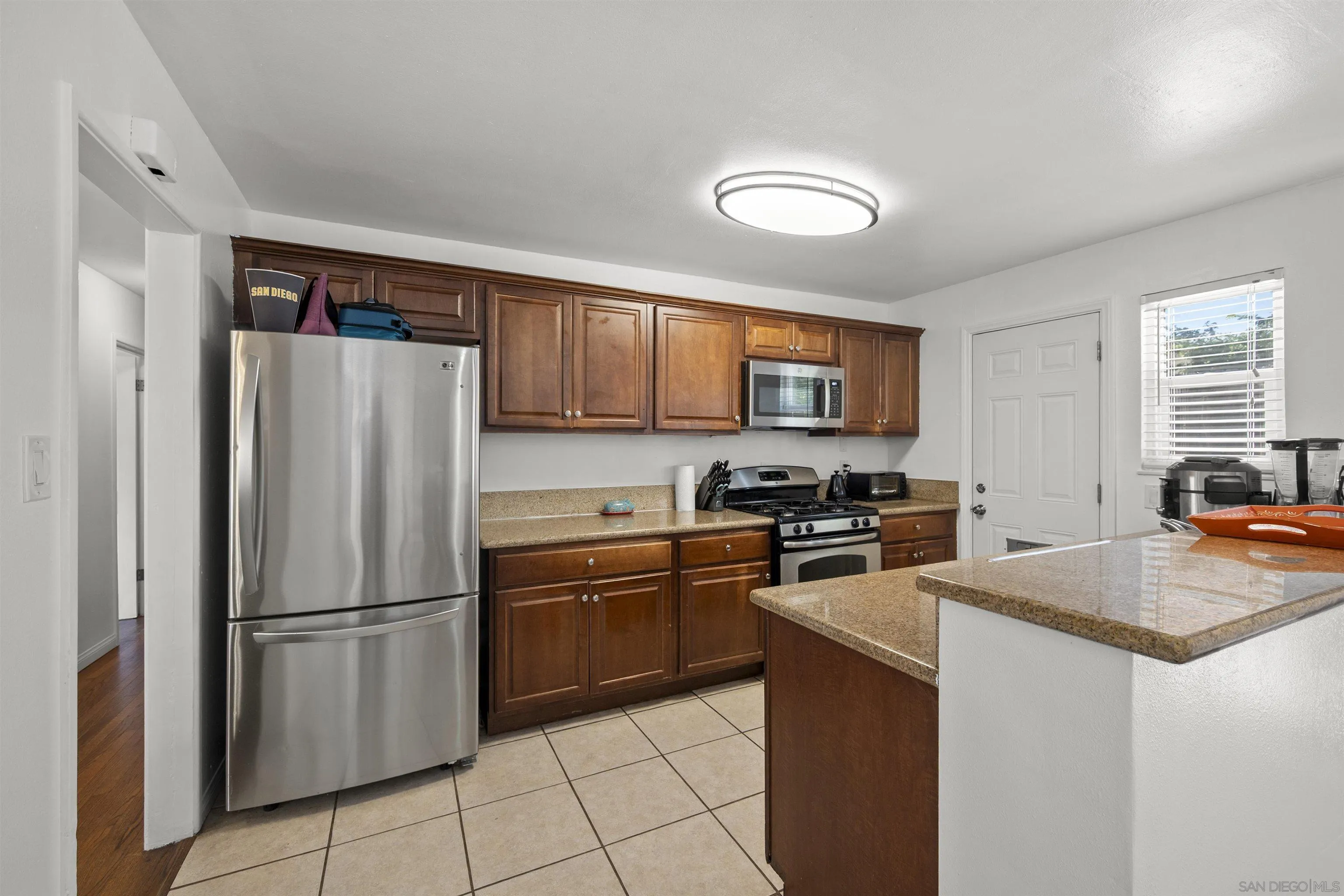 8740 Adriana Street Spring Valley, CA 91977 - Photo 9 of 32 a kitchen with stainless steel appliances granite countertop a refrigerator stove microwave and sink