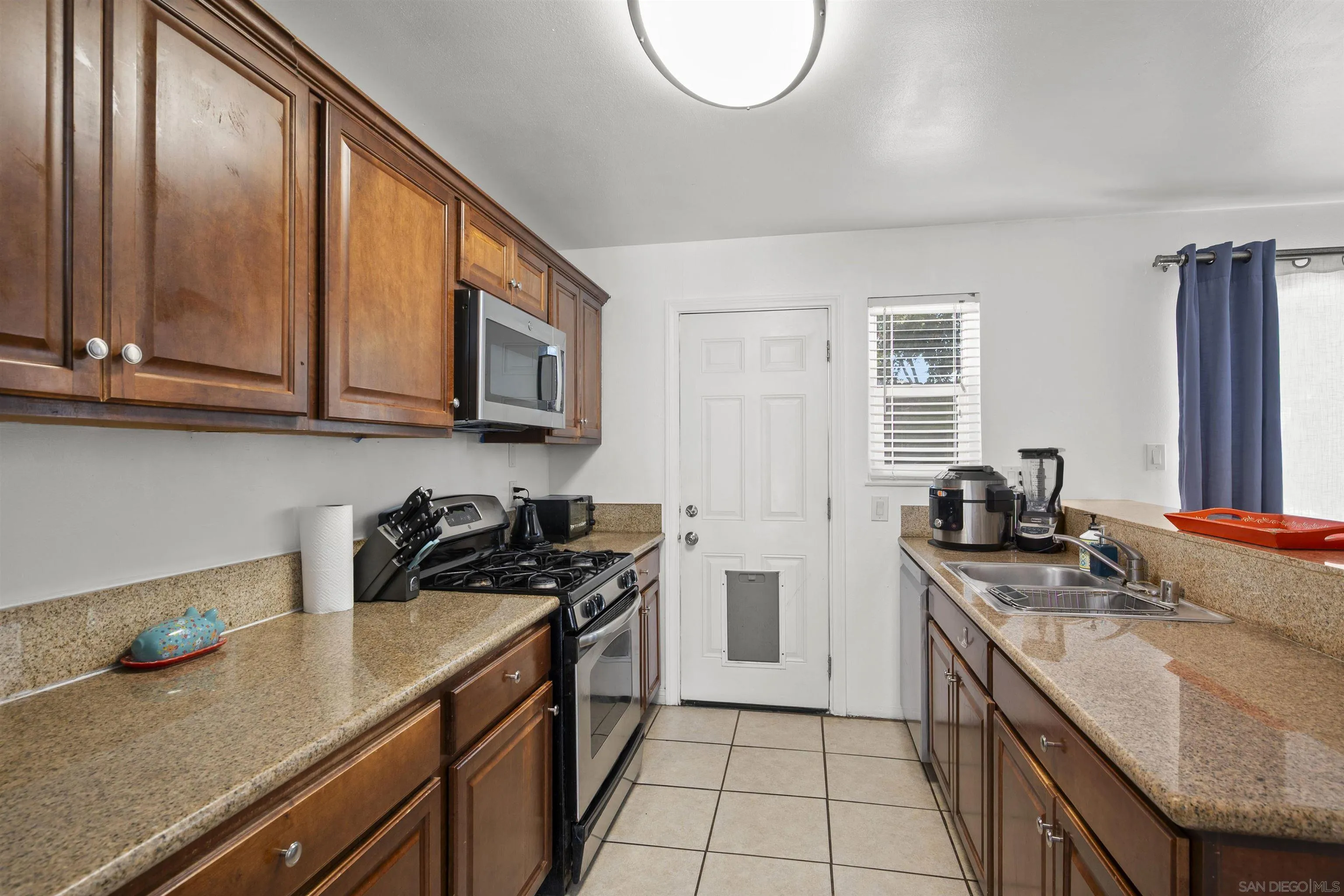 8740 Adriana Street Spring Valley, CA 91977 - Photo 10 of 32 a kitchen with stainless steel appliances granite countertop a sink stove and cabinets