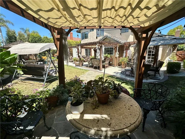 a view of a patio with table and chairs potted plants and large tree