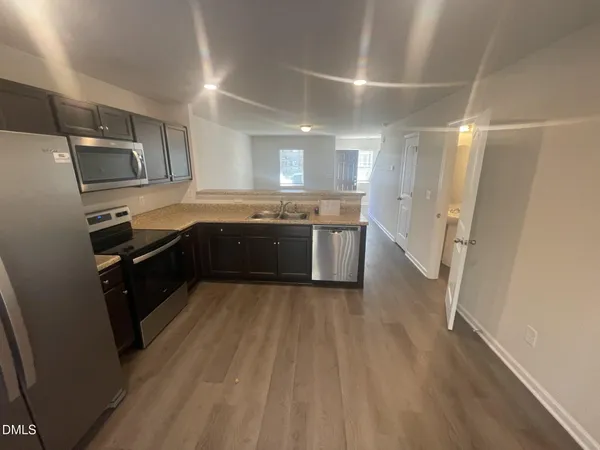 a large kitchen with a sink and dishwasher a stove top oven with wooden floor