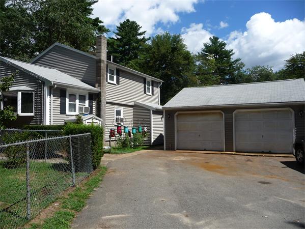 a front view of house with yard and trees in the background