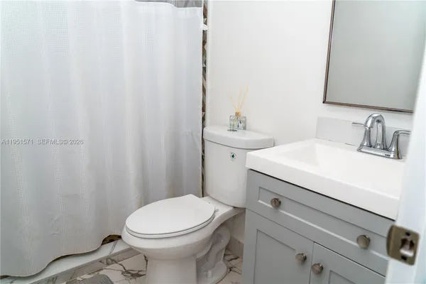 a bathroom with a sink a toilet and shower curtain