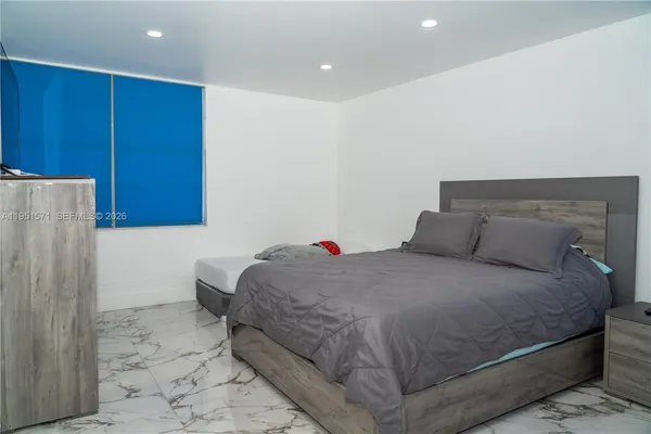 a bedroom with a bed and a refrigerator