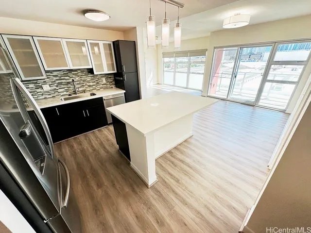 a living room with stainless steel appliances kitchen island granite countertop furniture large window and wooden floor
