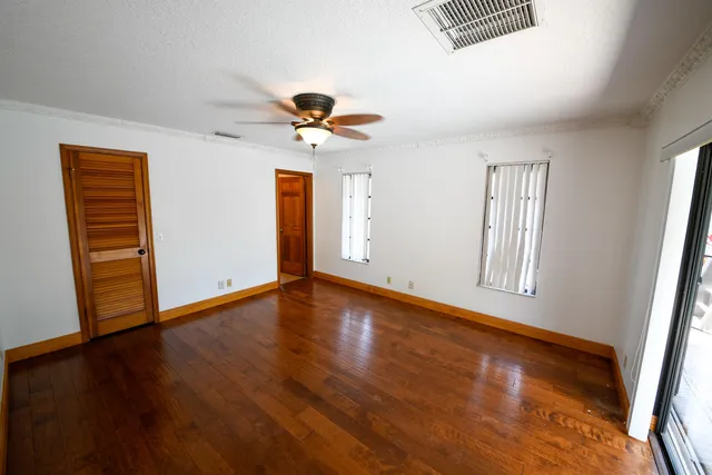 a view of an empty room with wooden floor and a window