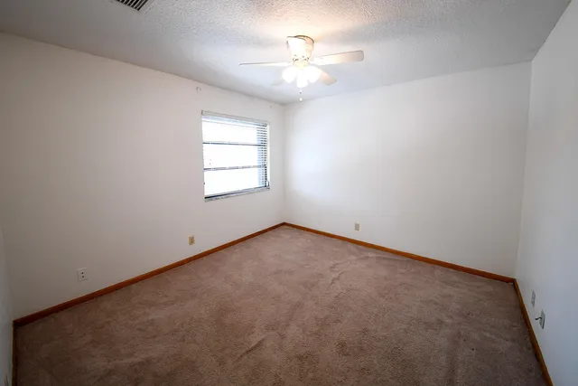a view of an empty room and chandelier fan