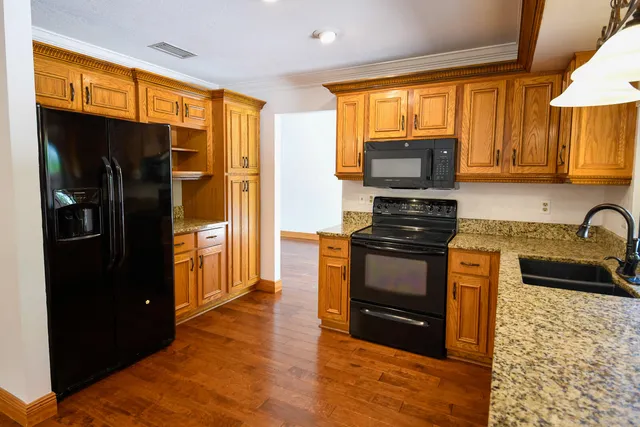 a kitchen with granite countertop a refrigerator stove top oven and sink